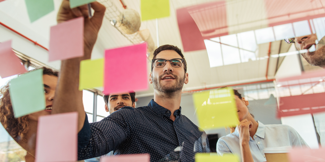 people putting postits on glass wall