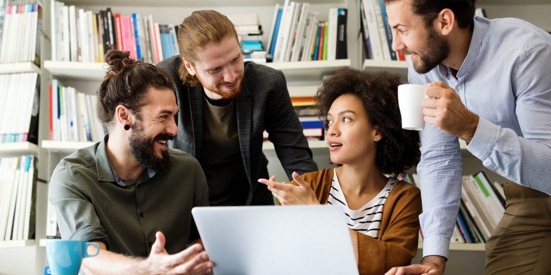 office workers sitting around open aptop talking